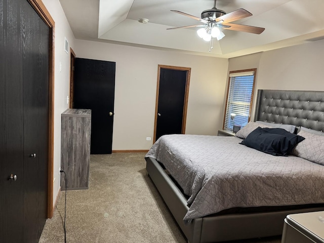 carpeted bedroom with a tray ceiling and ceiling fan