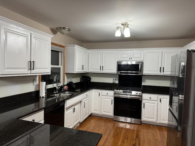 kitchen featuring white cabinetry, sink, stainless steel appliances, backsplash, and wood-type flooring