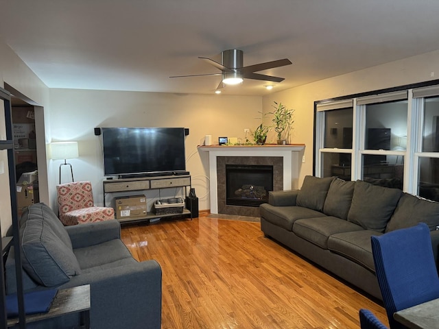 living room with hardwood / wood-style floors, ceiling fan, and a tiled fireplace