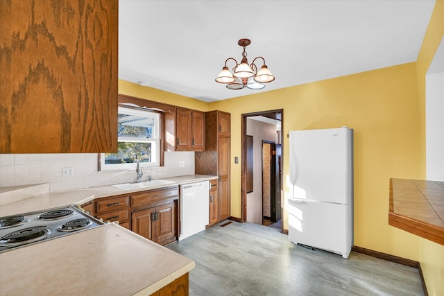 kitchen featuring decorative backsplash, a notable chandelier, sink, white appliances, and decorative light fixtures