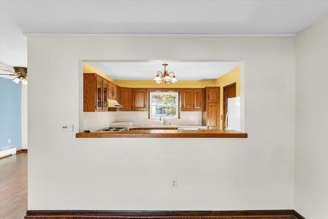 kitchen featuring kitchen peninsula, wood-type flooring, white fridge, and hanging light fixtures