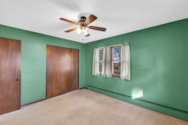 unfurnished bedroom with a baseboard heating unit, light carpet, ceiling fan, and a closet