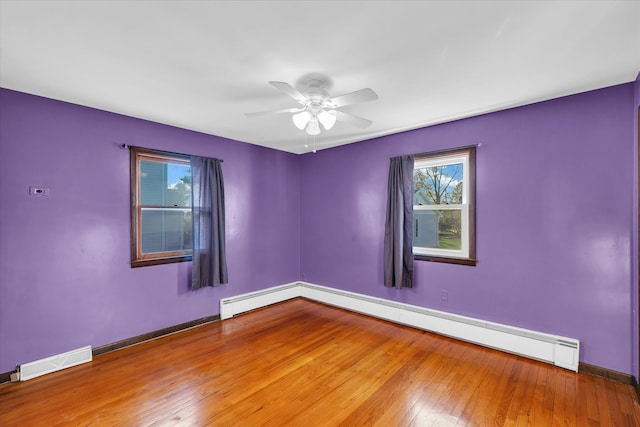 spare room featuring a baseboard radiator, wood-type flooring, and ceiling fan