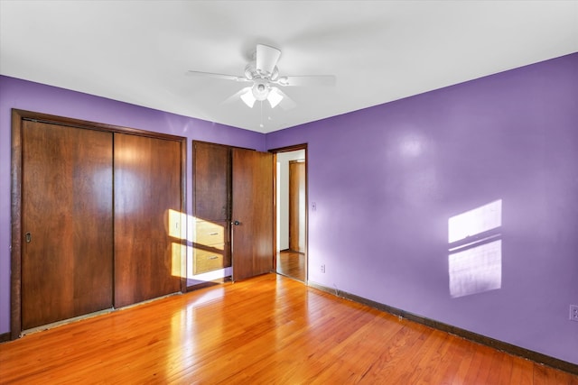 unfurnished bedroom with light hardwood / wood-style flooring, ceiling fan, and two closets