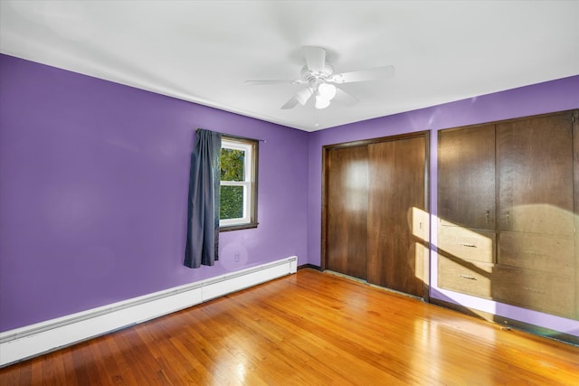 unfurnished bedroom with light hardwood / wood-style floors, ceiling fan, a baseboard radiator, and two closets