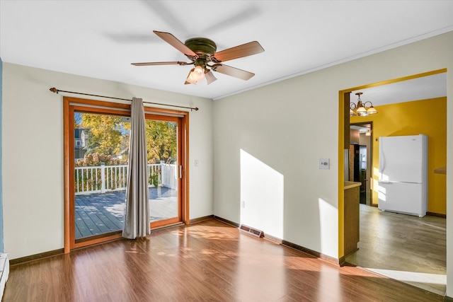 spare room with a baseboard radiator, wood-type flooring, ornamental molding, and ceiling fan with notable chandelier