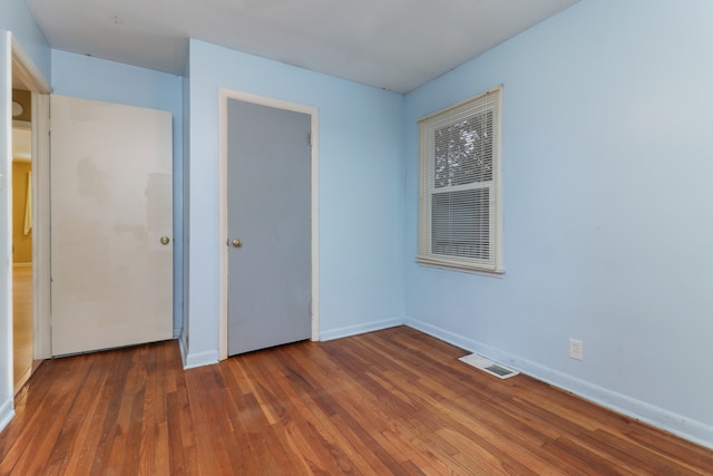 unfurnished bedroom with dark hardwood / wood-style flooring and a closet