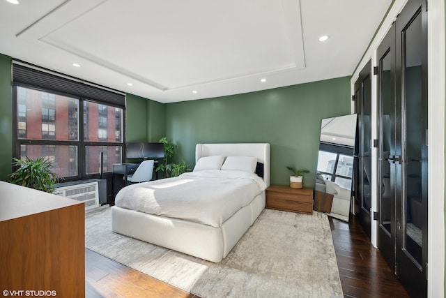 bedroom featuring hardwood / wood-style flooring, multiple windows, and a tray ceiling