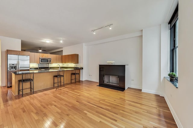 6 N Michigan Ave Unit 705, Chicago, IL 60602 - kitchen featuring appliances with stainless steel finishes, a breakfast bar area, light wood finished floors, dark countertops, and a fireplace with flush hearth