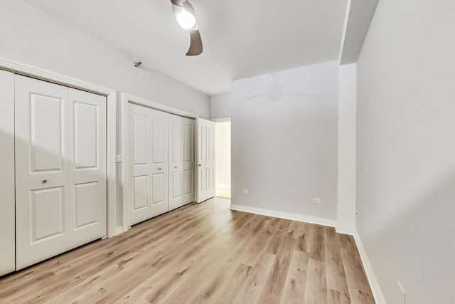 unfurnished bedroom with multiple closets, light wood-type flooring, and baseboards