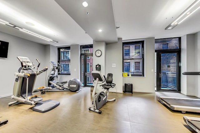 exercise room featuring floor to ceiling windows and baseboards