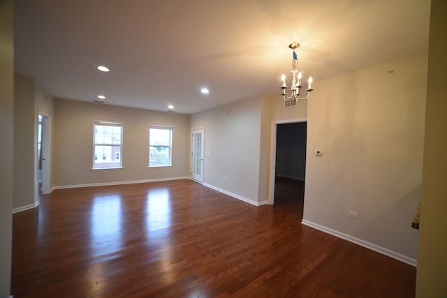 spare room with dark hardwood / wood-style flooring and a notable chandelier