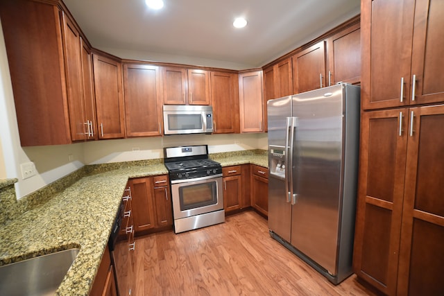 kitchen with stainless steel appliances, light hardwood / wood-style floors, and light stone counters