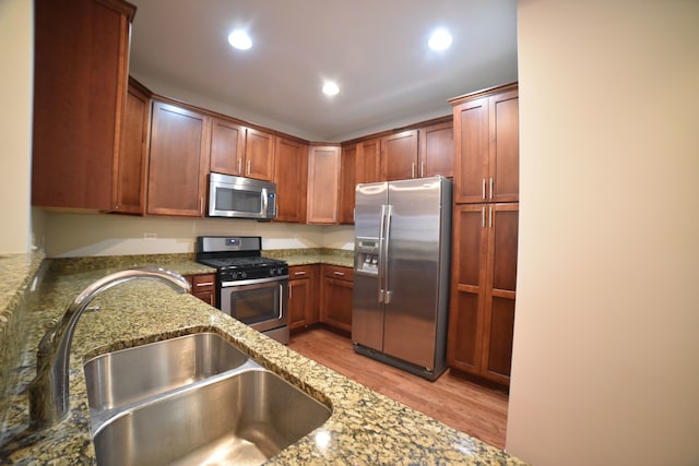 kitchen featuring light stone countertops, stainless steel appliances, sink, and light hardwood / wood-style flooring