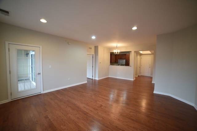 unfurnished living room featuring dark hardwood / wood-style flooring and a chandelier