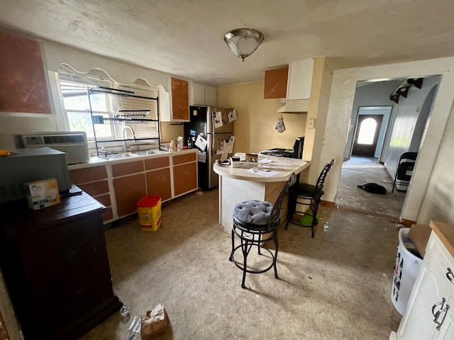 kitchen featuring a kitchen bar, stainless steel refrigerator, sink, and tile counters