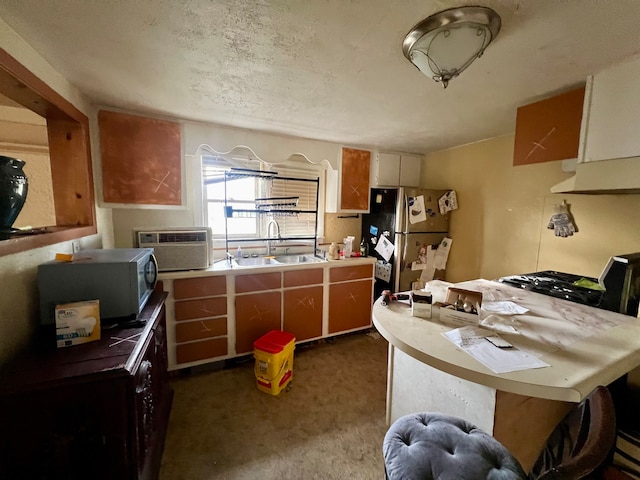 kitchen featuring stainless steel refrigerator, sink, a wall mounted AC, dark carpet, and black range