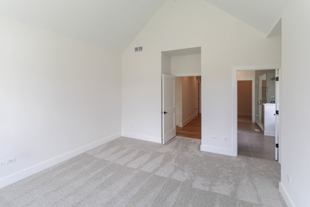 unfurnished bedroom with high vaulted ceiling and light carpet