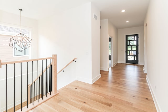 hallway with light wood-type flooring and an inviting chandelier