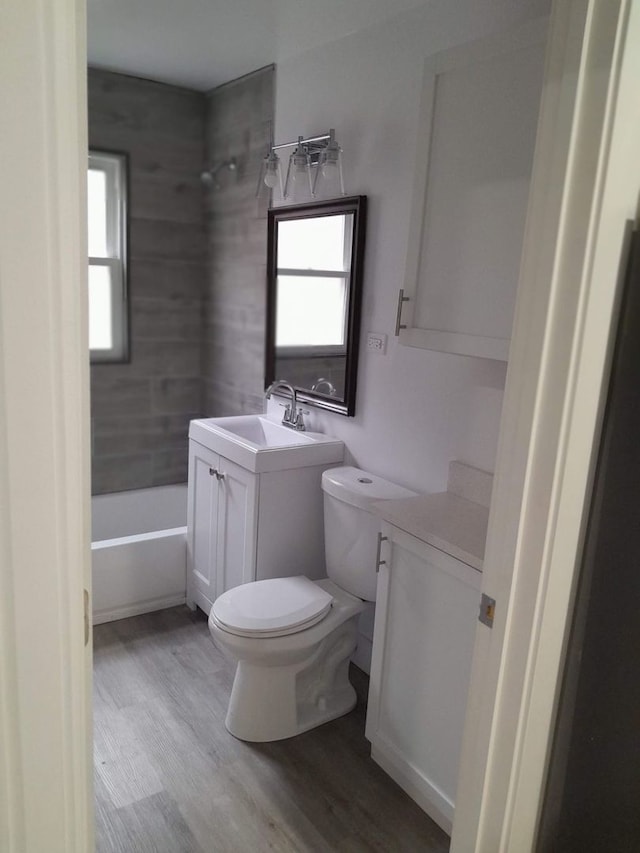 full bathroom with toilet, tiled shower / bath combo, vanity, and hardwood / wood-style flooring