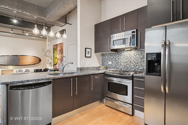 kitchen with rail lighting, sink, hanging light fixtures, stainless steel appliances, and light wood-type flooring