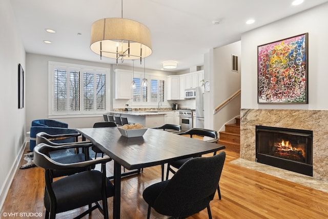 dining room with a premium fireplace, sink, and light hardwood / wood-style floors