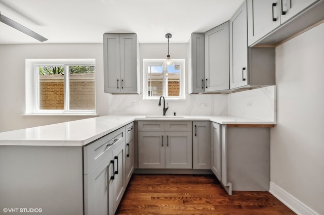 kitchen with sink, kitchen peninsula, tasteful backsplash, pendant lighting, and dark hardwood / wood-style flooring