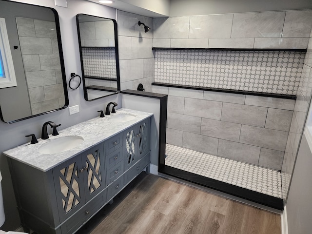 bathroom with wood-type flooring, vanity, and tiled shower