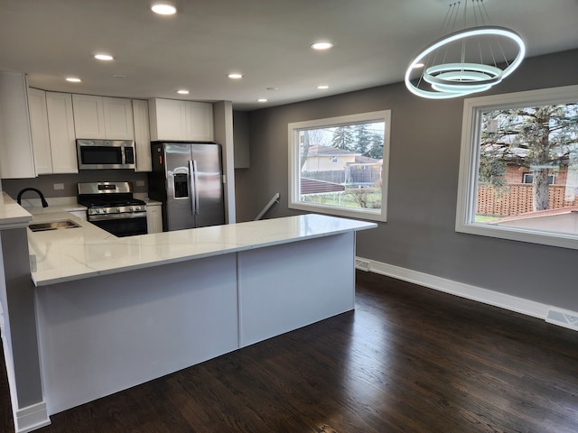 kitchen featuring stainless steel appliances, sink, decorative light fixtures, and kitchen peninsula