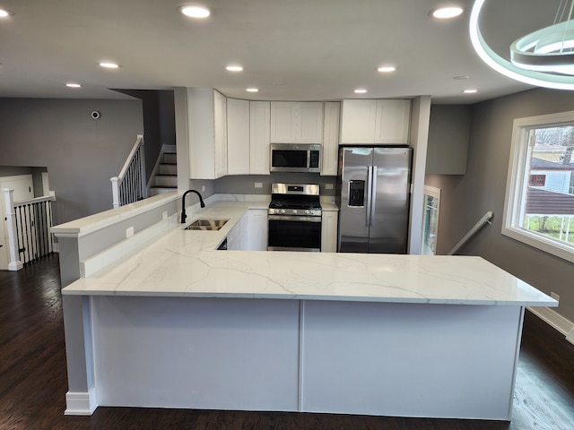 kitchen featuring light stone countertops, dark hardwood / wood-style floors, sink, and appliances with stainless steel finishes