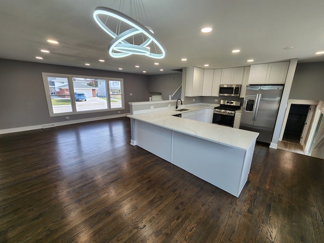 kitchen featuring stainless steel appliances, decorative light fixtures, dark hardwood / wood-style flooring, sink, and kitchen peninsula