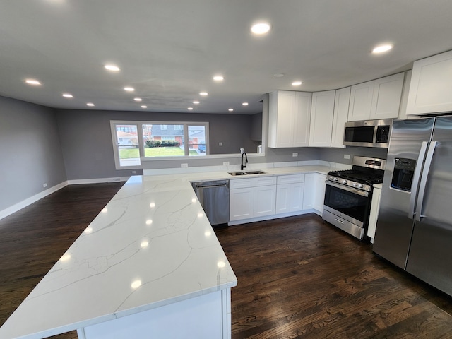 kitchen featuring dark wood-type flooring, white cabinets, sink, light stone countertops, and appliances with stainless steel finishes