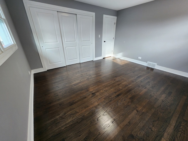 unfurnished bedroom featuring dark wood-type flooring and a closet