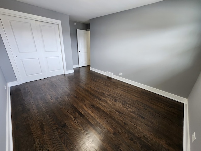 unfurnished bedroom featuring dark wood-type flooring and a closet