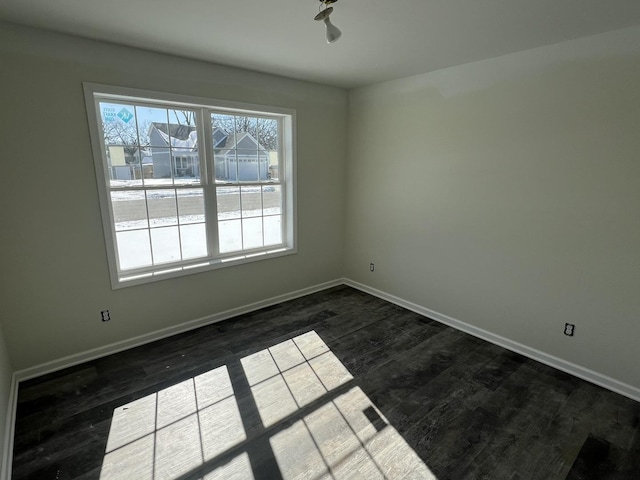 unfurnished room with dark wood-style floors, a wealth of natural light, and baseboards