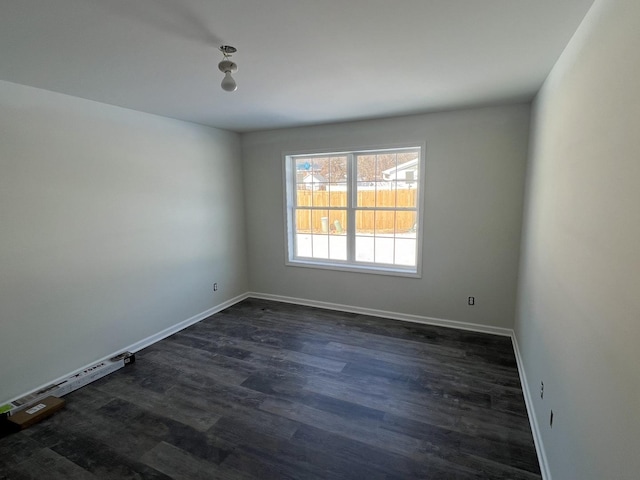 empty room with dark wood finished floors and baseboards