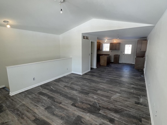 unfurnished living room featuring dark wood-type flooring, lofted ceiling, and baseboards