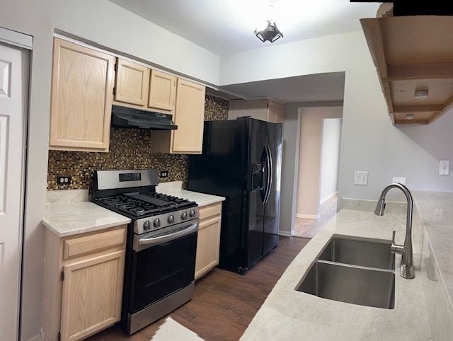 kitchen featuring gas range, dark hardwood / wood-style floors, black fridge, and sink