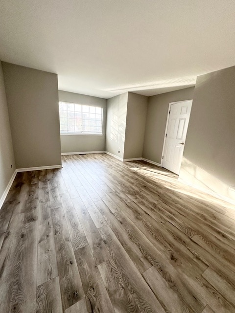 kitchen with light brown cabinetry, stainless steel dishwasher, black range with gas stovetop, sink, and hardwood / wood-style flooring