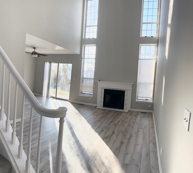 living room featuring a towering ceiling, light hardwood / wood-style flooring, and ceiling fan