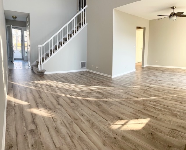 unfurnished living room featuring ceiling fan, light hardwood / wood-style floors, and a high ceiling