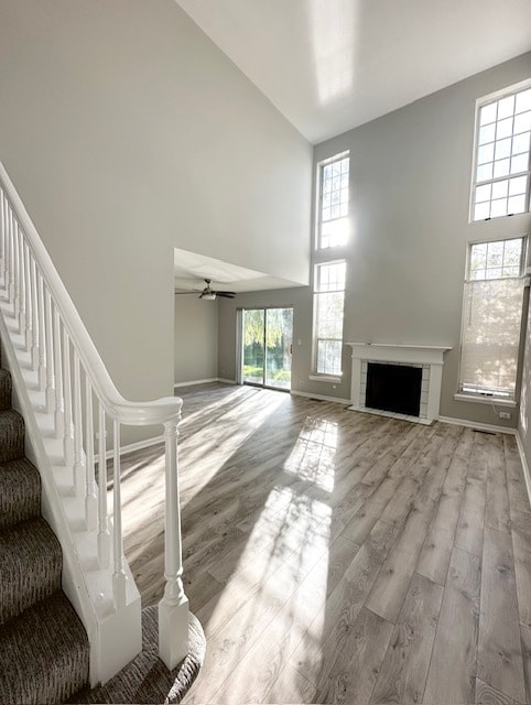 living room featuring light wood-type flooring, a towering ceiling, and ceiling fan