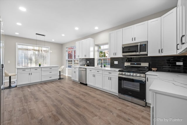 kitchen with stainless steel appliances, white cabinets, and sink