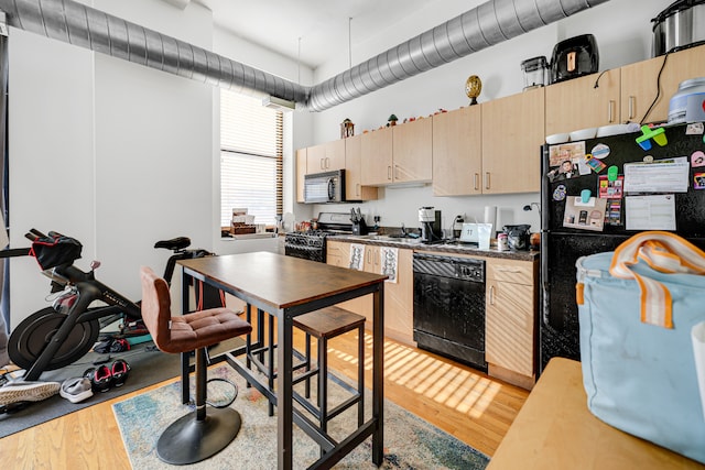 kitchen with black appliances, light brown cabinetry, and light hardwood / wood-style floors