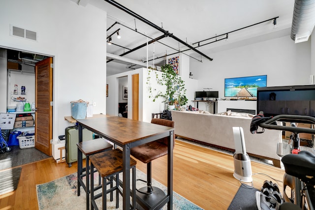 dining room featuring wood-type flooring and a towering ceiling