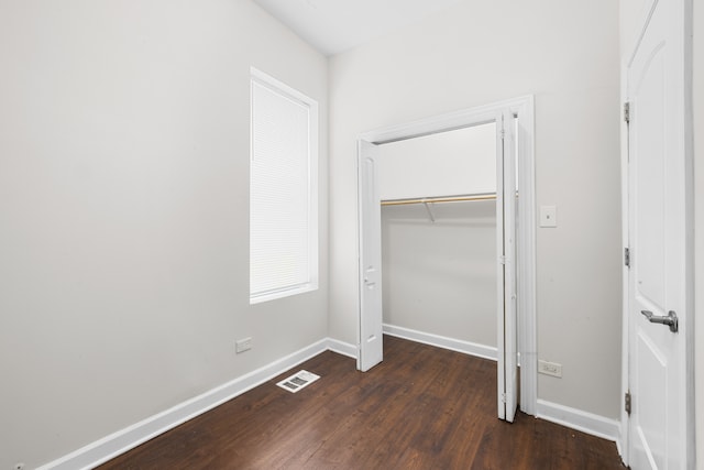 unfurnished bedroom featuring dark wood-type flooring and a closet