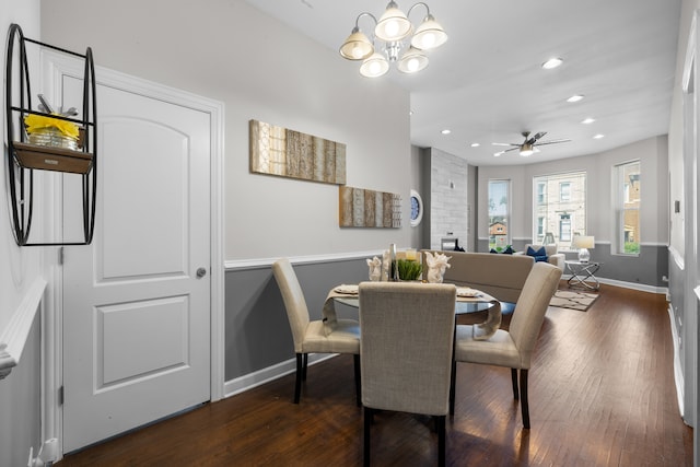 dining room with dark hardwood / wood-style flooring and ceiling fan with notable chandelier