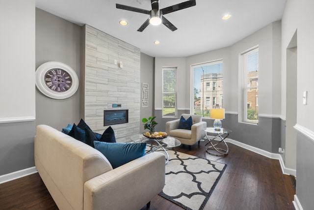 living room featuring a large fireplace, dark hardwood / wood-style floors, and ceiling fan