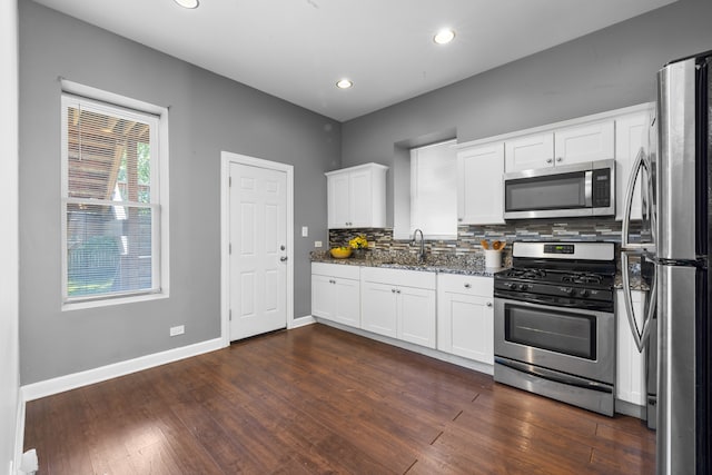 kitchen featuring dark stone counters, white cabinetry, dark wood-type flooring, and stainless steel appliances