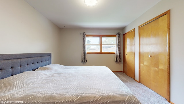 bedroom with multiple closets and light colored carpet